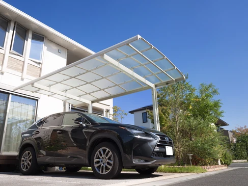 Sc&egrave;ne ext&eacute;rieure r&eacute;sidentielle avec v&eacute;hicule SUV noir stationn&eacute; sous un carport moderne