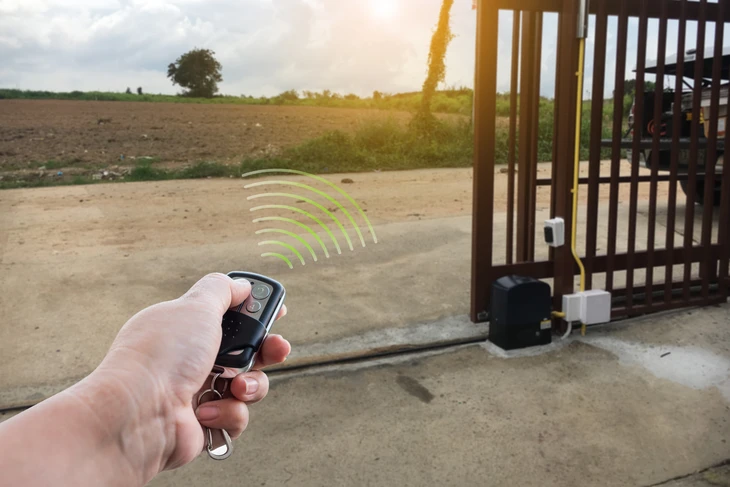 Une personne assise dans un v&eacute;hicule utilise une t&eacute;l&eacute;commande de garage pour ouvrir une porte sectionnelle blanche