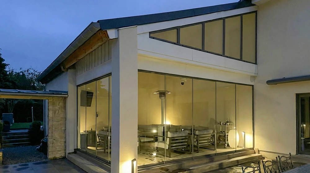 Clôture aluminium gris anthracite avec bande décorative rouge ajourée à motifs végétaux abstraits, devant pavillon de plain-pied blanc aux encadrements rouges assortis