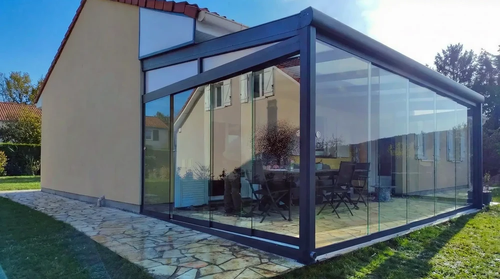 Ext&eacute;rieur r&eacute;sidentiel avec v&eacute;randa vitr&eacute;e moderne attenante &agrave; maison traditionnelle