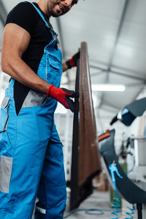 Deux ouvriers d'usine assemblant des cadres de fen&ecirc;tres en PVC sur une ligne de production, d&eacute;montrant le travail d'&eacute;quipe et les comp&eacute;tences dans un environnement industriel occup&eacute;