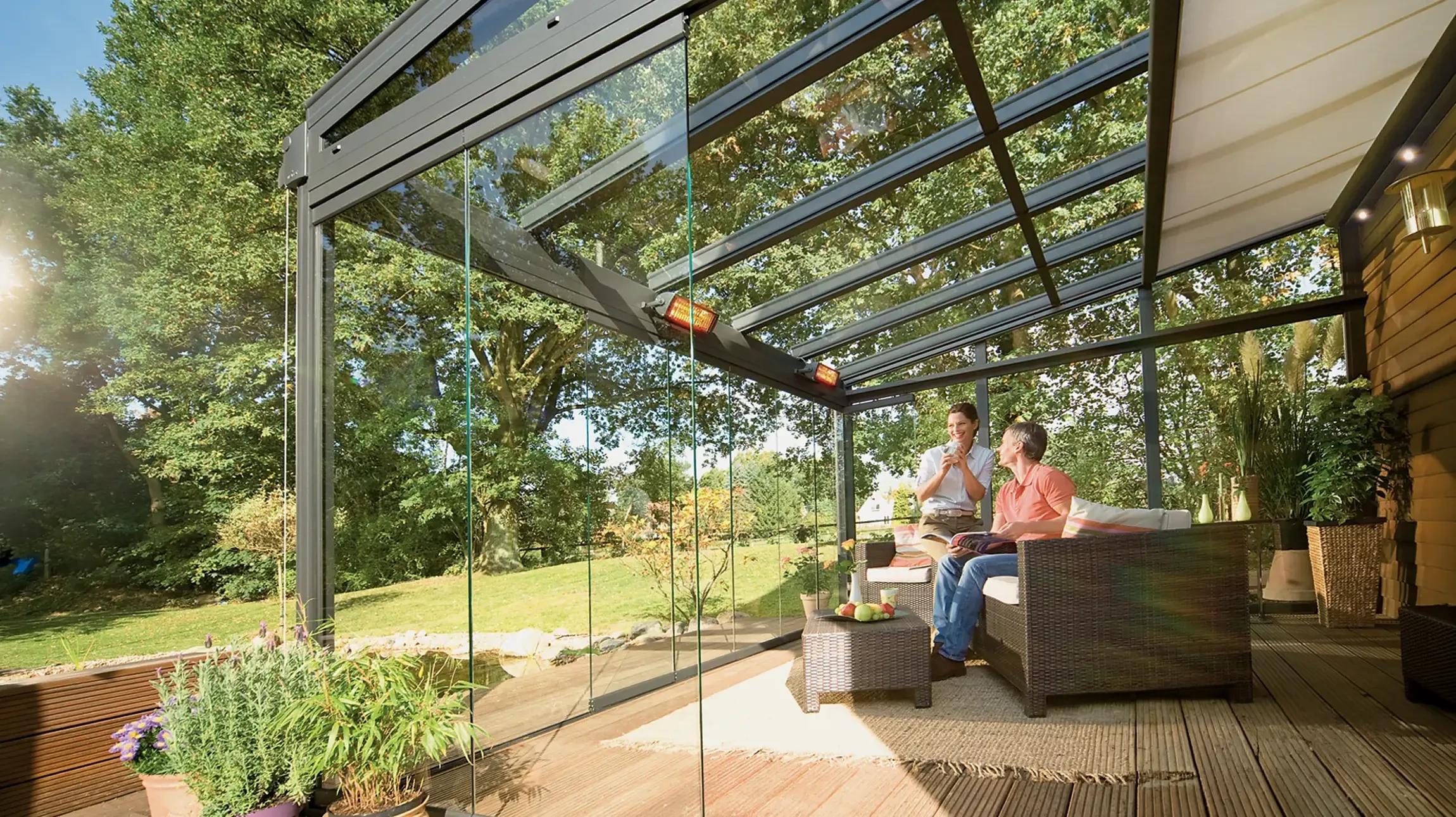 Maison individuelle moderne avec terrasse couverte, pergola métallique et mobilier extérieur sur pelouse entretenue sous ciel bleu dégagé
